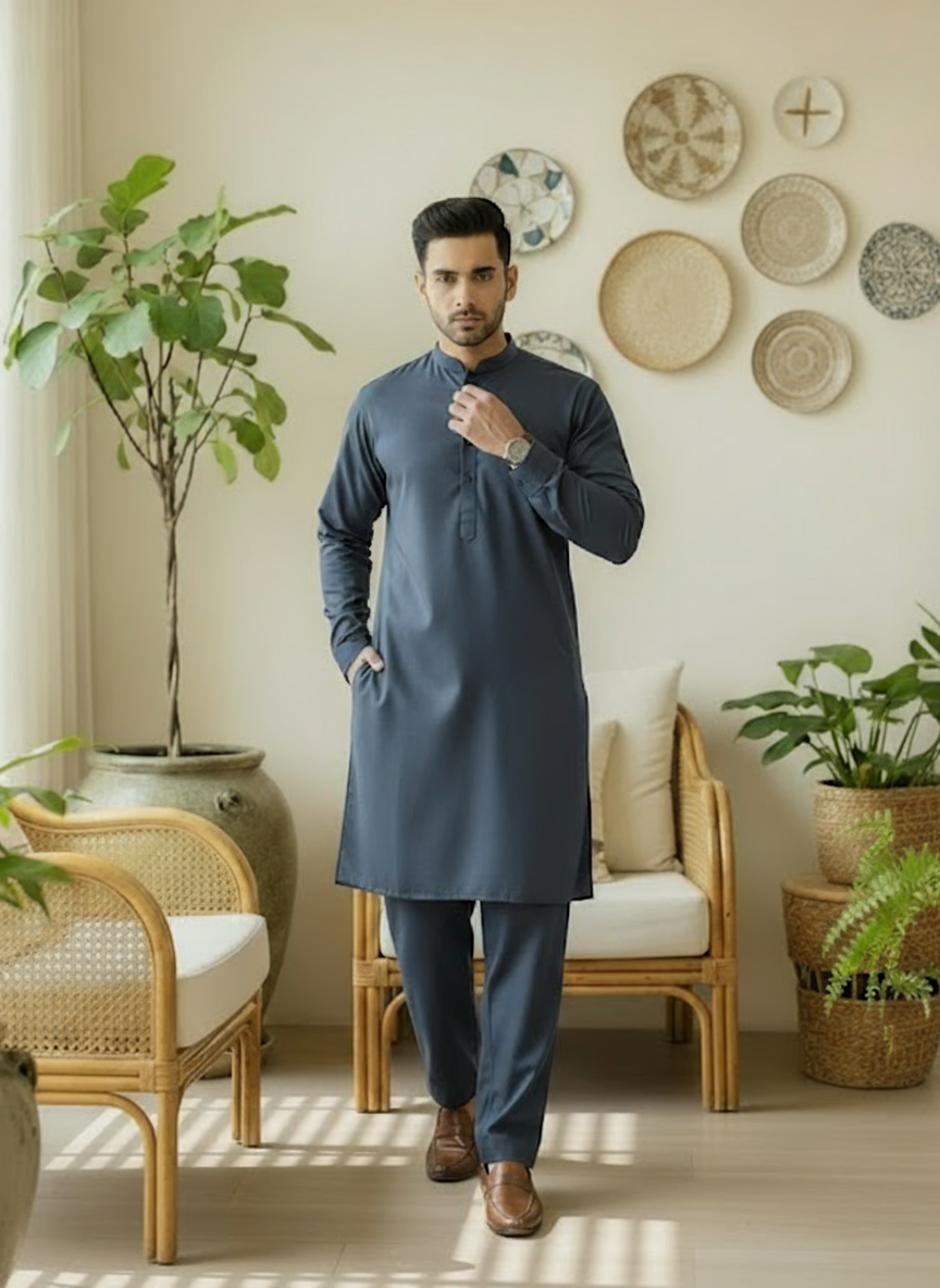 Man in a oxford blue kurta shlawar standing in a room